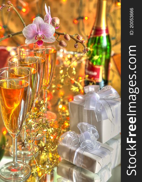 Glasses of champagne,gift boxes,bottle and flowers on gold background. Glasses of champagne,gift boxes,bottle and flowers on gold background.