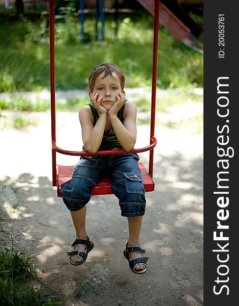 Little boy sitting on a swing