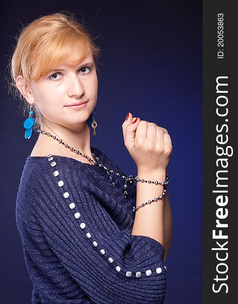 Red-haired girl in a blue blouse with a blue background with beads. Red-haired girl in a blue blouse with a blue background with beads