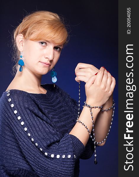 Red-haired girl in a blue blouse with a blue background with beads. Red-haired girl in a blue blouse with a blue background with beads