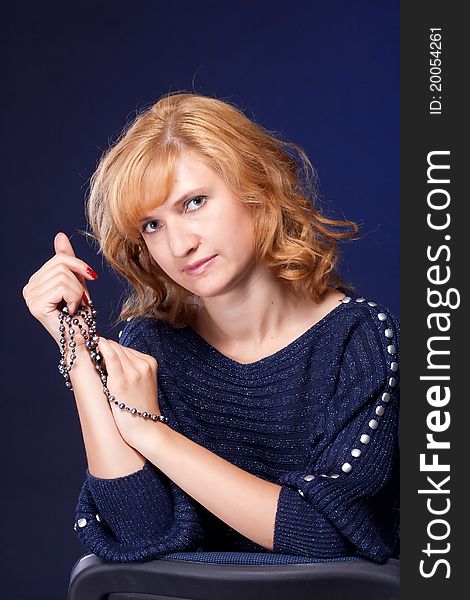 Red-haired girl in a blue blouse with a blue background with beads. Red-haired girl in a blue blouse with a blue background with beads
