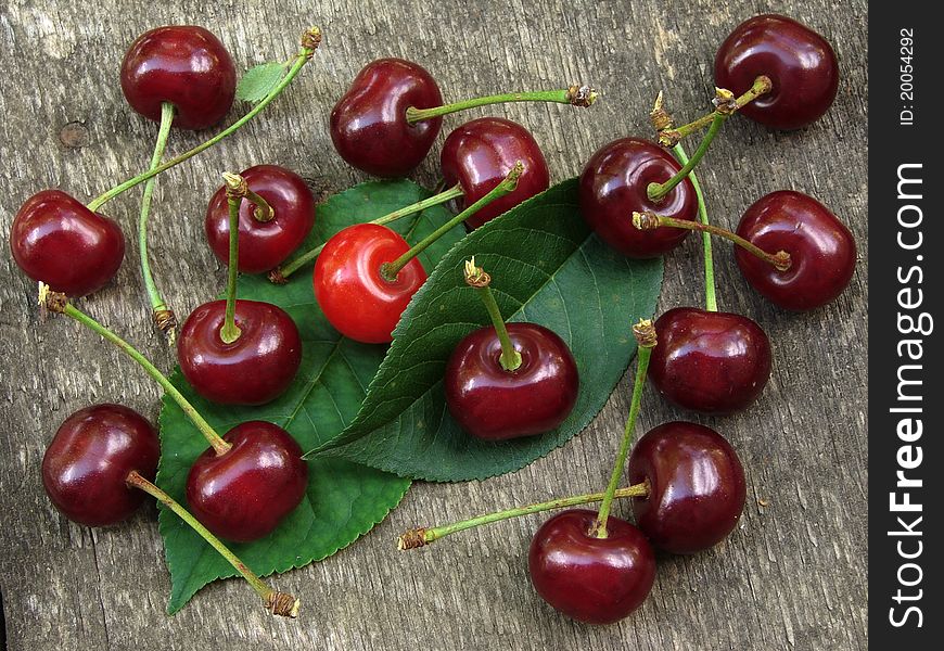 Some cherry fruits with leaves on old wooden background