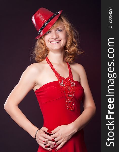 Red-haired girl in a red dress and red hat. Studio photography