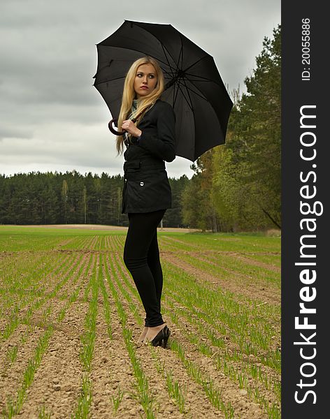 Beautiful blondy girl with umbrella looking back