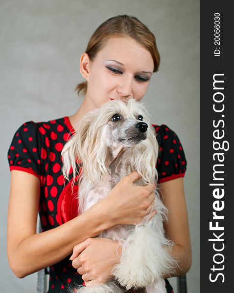 The beautiful girl and chinese crested dog on grey background. Shallow DOF, focus on the nose of the dog