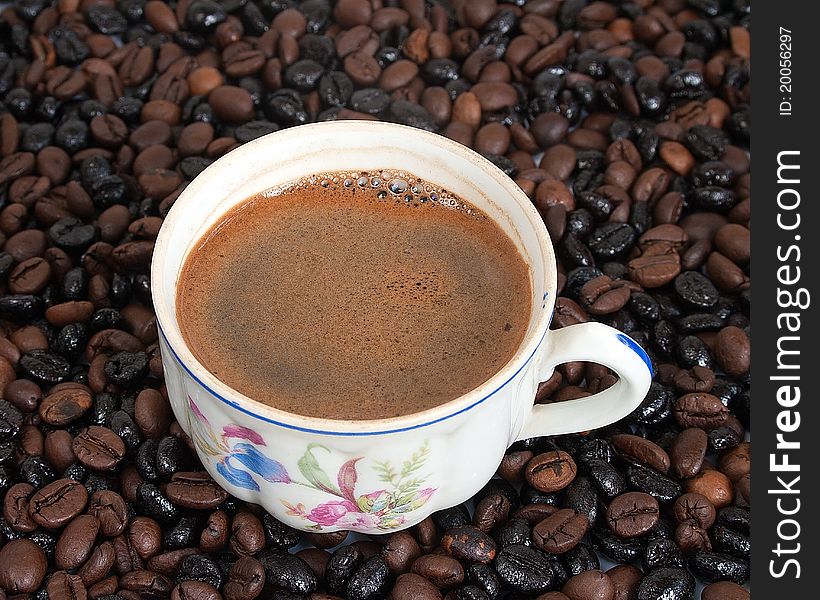 The cup of coffee on coffee-beans background