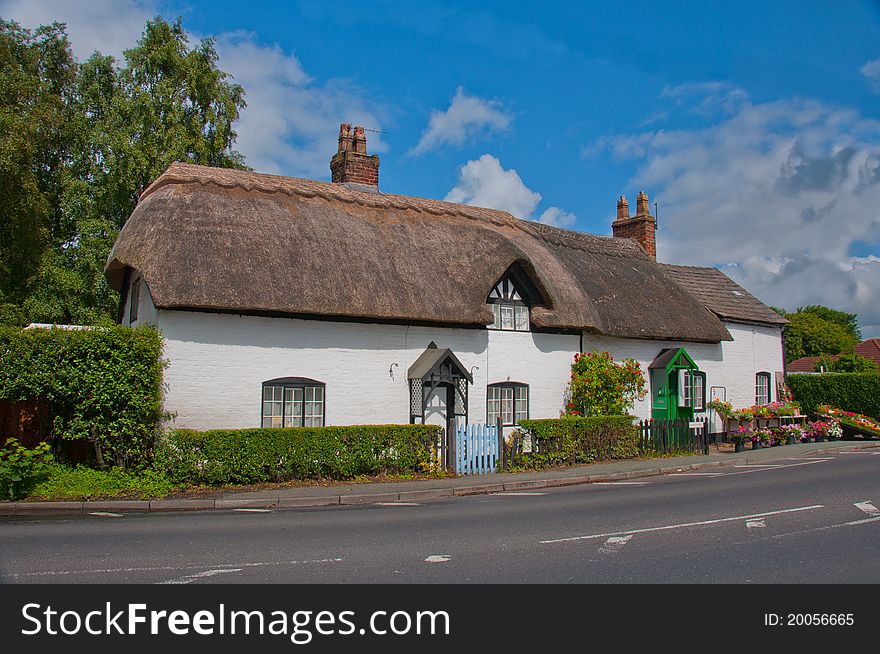 Traditional English country cottage exterior with flowers on display. Traditional English country cottage exterior with flowers on display.