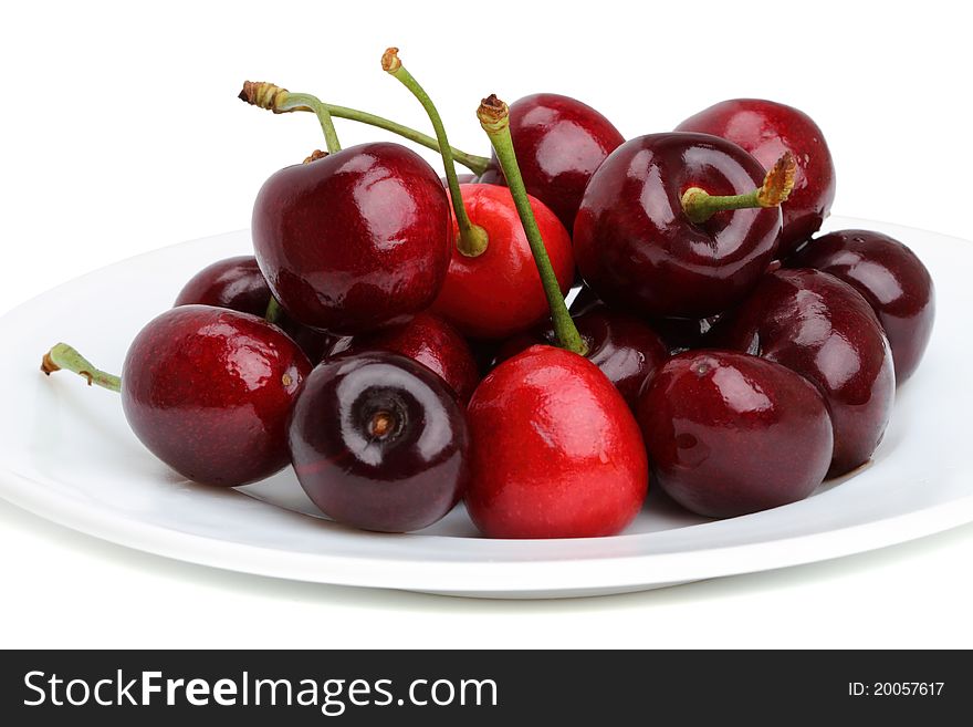 Ripe cherries on a white plate. Isolated on a white background