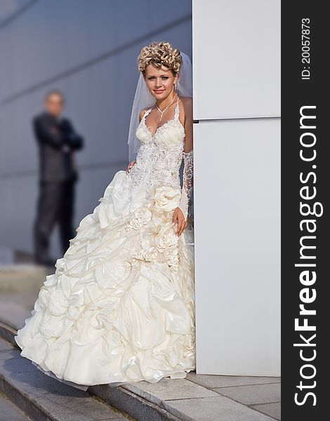 Caucasian mid-adult bride and groom standing on porch looking at viewer and smiling.
