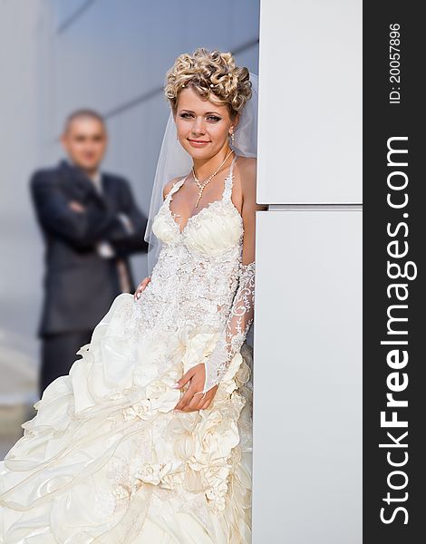 Caucasian mid-adult bride and groom standing on porch looking at viewer and smiling.