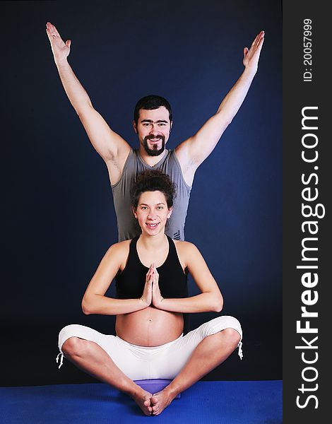 Beautiful pregnant young woman practicing yoga with husband. Beautiful pregnant young woman practicing yoga with husband