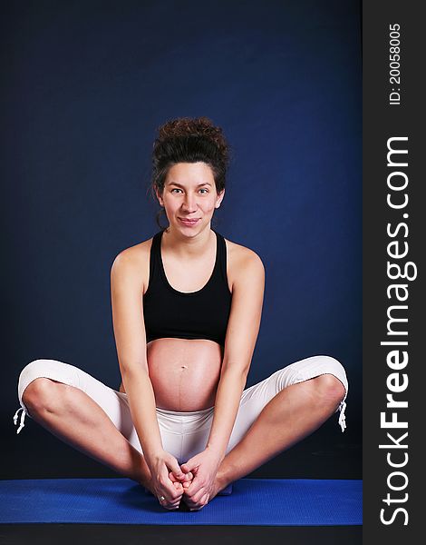 Beautiful pregnant young woman practicing yoga on black. Beautiful pregnant young woman practicing yoga on black