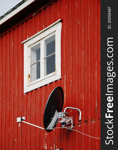 Satellite antenna on wall of small wooden house. Satellite antenna on wall of small wooden house.