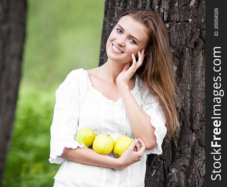 Beautiful happy young woman with apples in the park  on a warm summer day