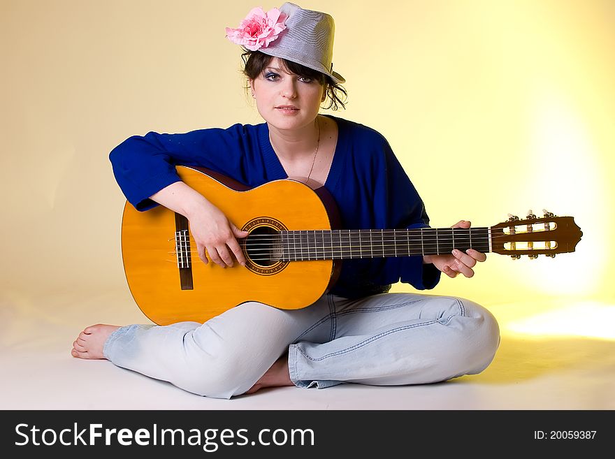 Romantic girl sitting with the guitar on yellow background. Romantic girl sitting with the guitar on yellow background