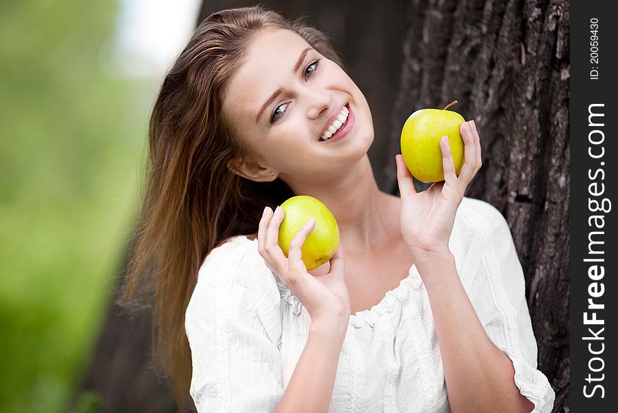 Beautiful happy young woman with apples in the park  on a warm summer day