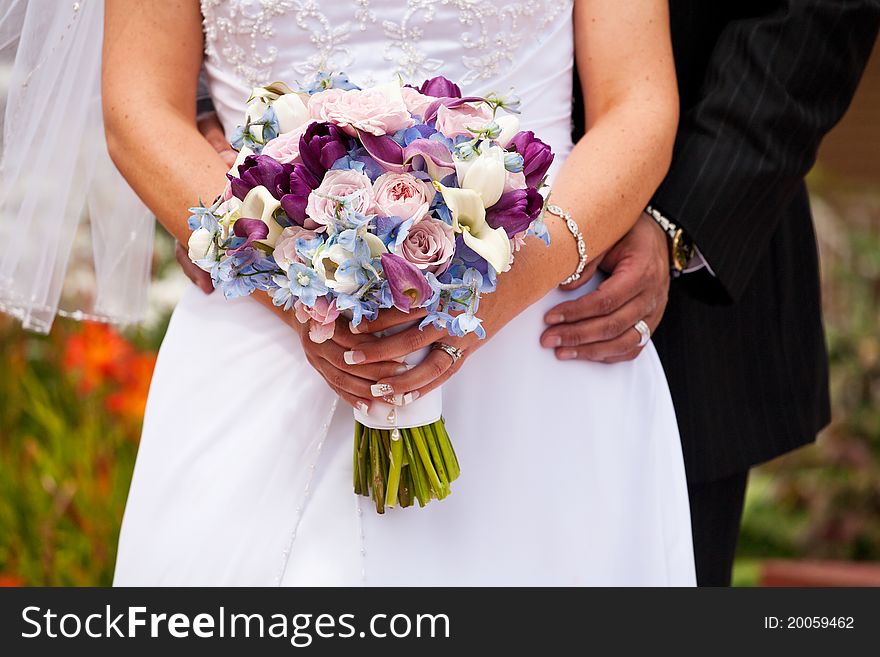 Bride and groom holding bridal bouquet. Bride and groom holding bridal bouquet