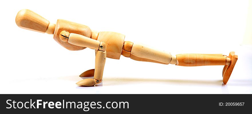 Wooden mannequin doing pushups against white background.