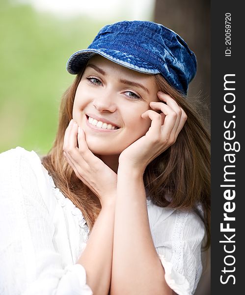 Happy young woman wearing a cap in the park on a warm summer day. Happy young woman wearing a cap in the park on a warm summer day