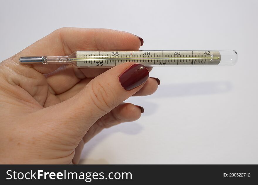 A woman`s hand holds a mercury thermometer for measuring body temperature