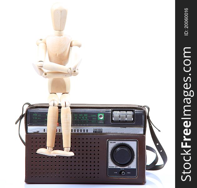 Wooden mannequin sitting on old radio. Wooden mannequin sitting on old radio.