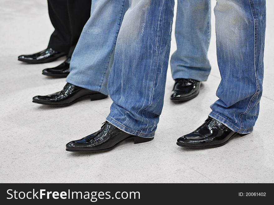 Men's feet in black leather shoes and jeans