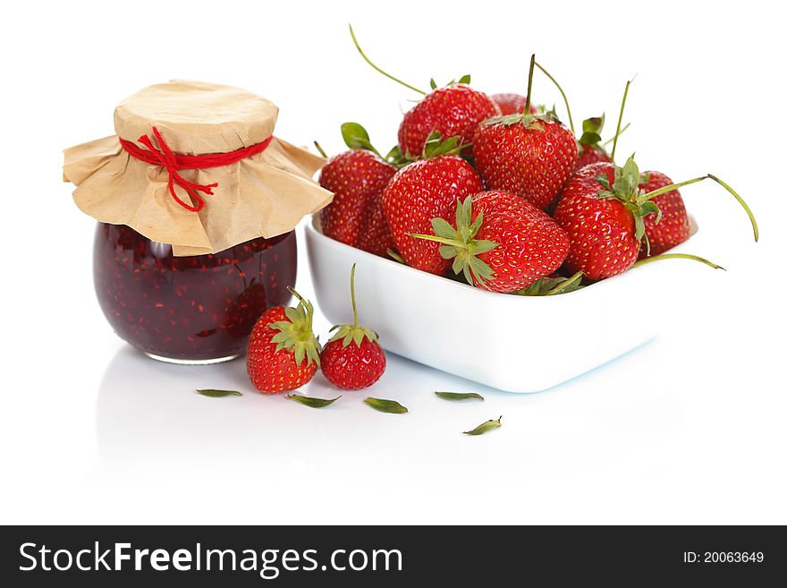 A bowl of fresh strawberries with a jam pot. A bowl of fresh strawberries with a jam pot