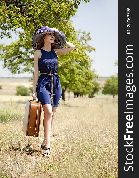 Lonely girl with suitcase at countryside. Outdoor photo.