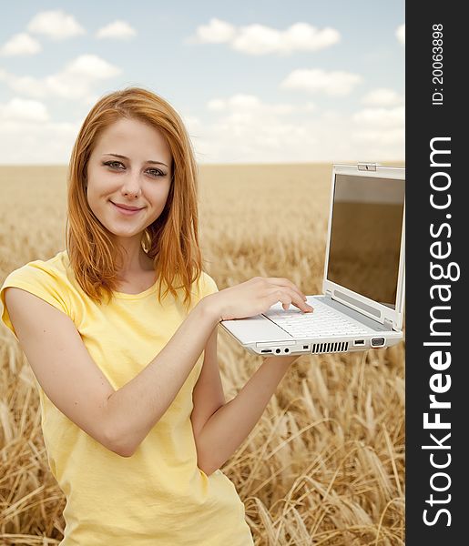 Girl with laptop at wheat field.