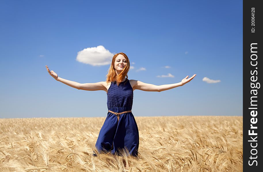 Redhead girl at wheat field in summer day.