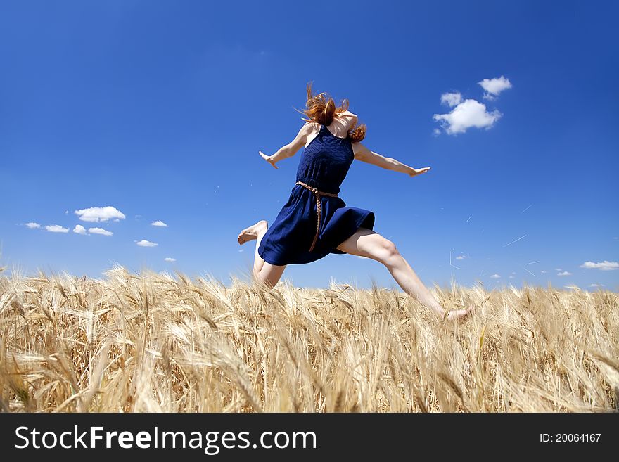 Redhead girl at wheat field in summer day.