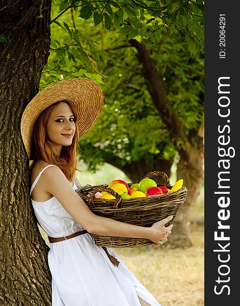 Beautiful redhead girl with fruit at garden.