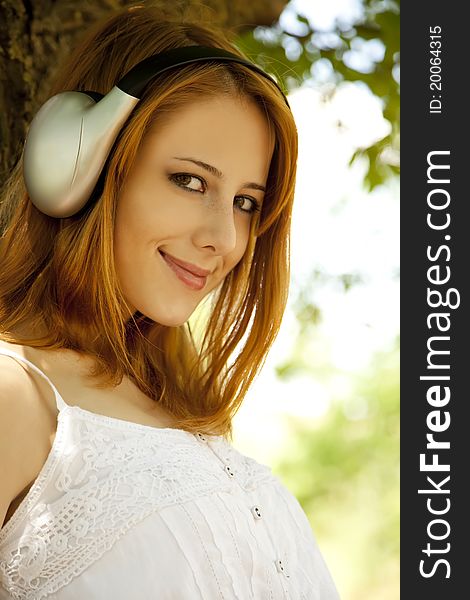 Redhead Girl With Headphones At Garden.