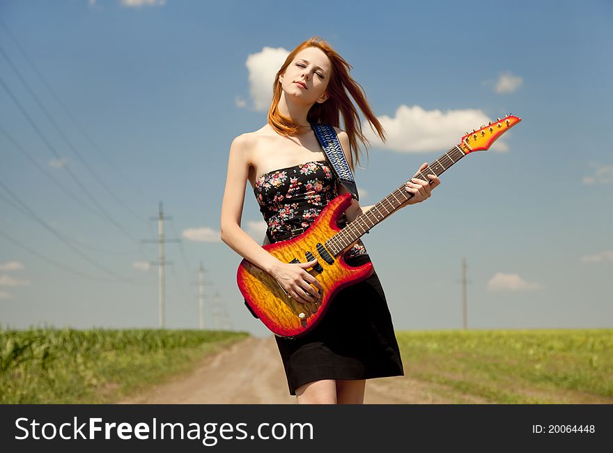 Rock girl with guitar at countryside.