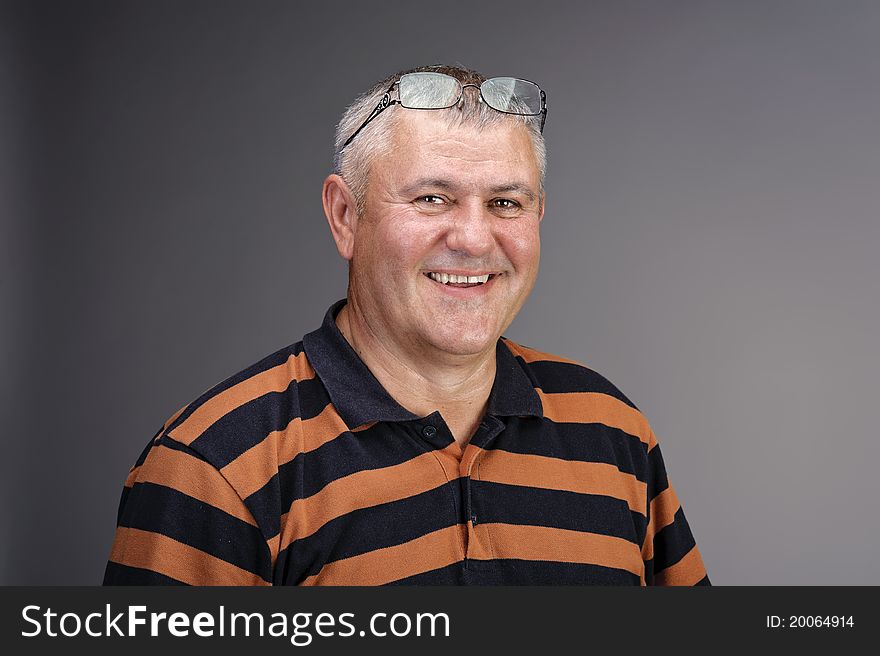 Stuidio portrait of a smiling man in stripped T-shirt over gray background