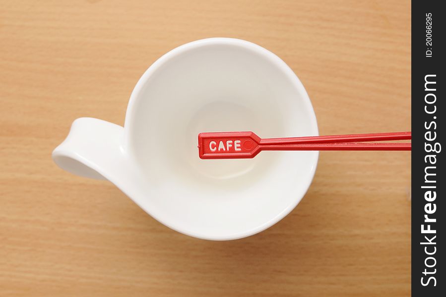 White cup with the red spoon on wodden table. White cup with the red spoon on wodden table