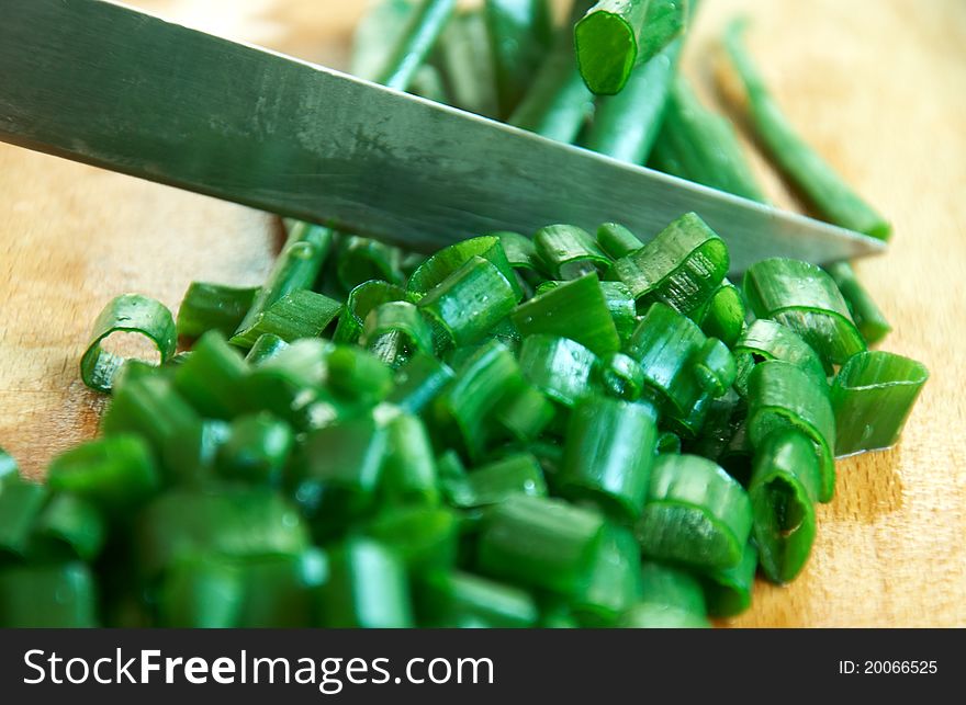 Spring onions cutting with knife on wooden board