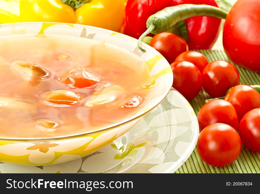 Tomato soup on a background of fresh tomatoes and hot peppers