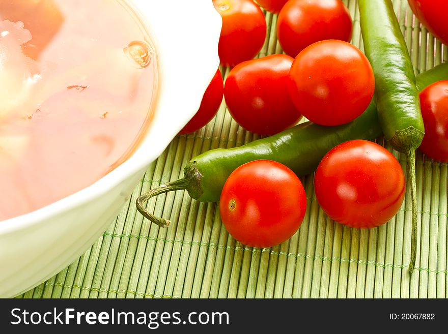 Tomato soup on a background of fresh tomatoes and hot peppers