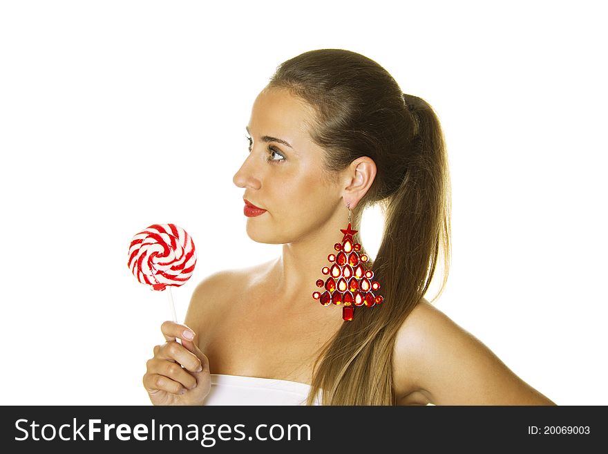 Close-up of a beautiful young woman with a lollipop and big earrings made ??of precious red stone in the form of a Christmas tree. Isolated. Close-up of a beautiful young woman with a lollipop and big earrings made ??of precious red stone in the form of a Christmas tree. Isolated