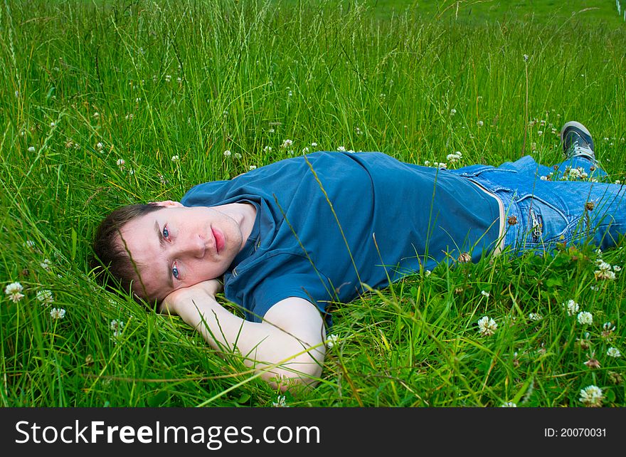 The young man lies on a green meadow