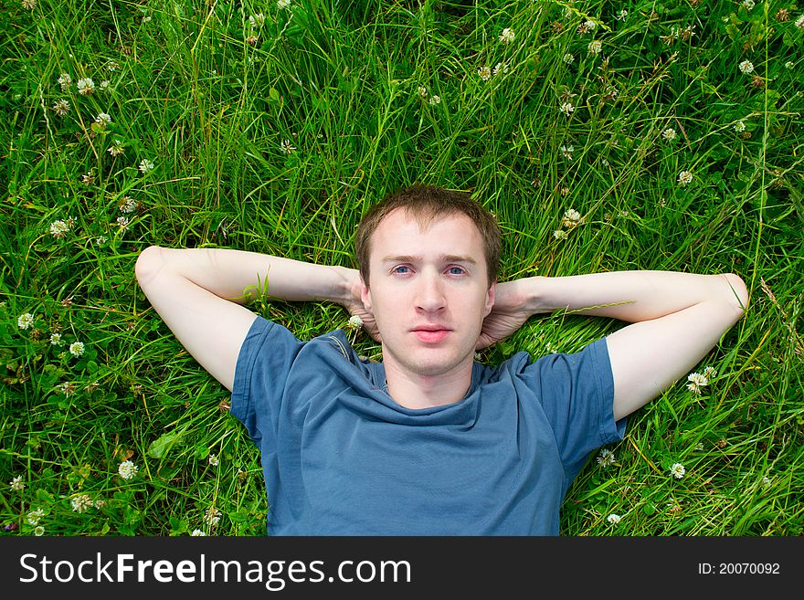 The young man lies on a green meadow alone