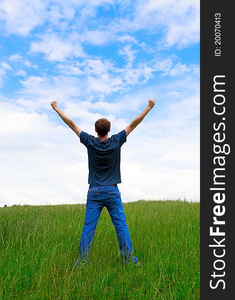 The young man on a meadow having lifted hands upwards