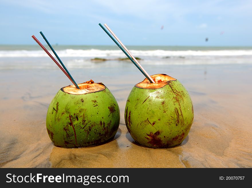 Two tropical cocktails standing in water on the beach