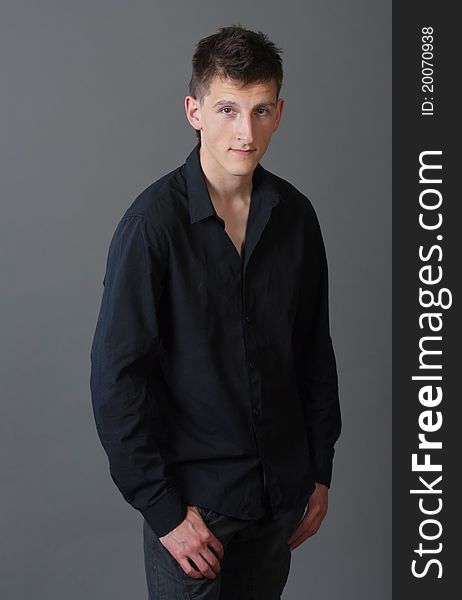 Attractive young male person standing against gray background