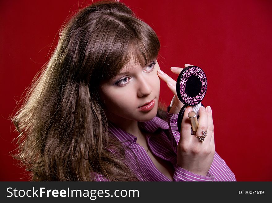 Close up of woman looking into mirror,on a red background