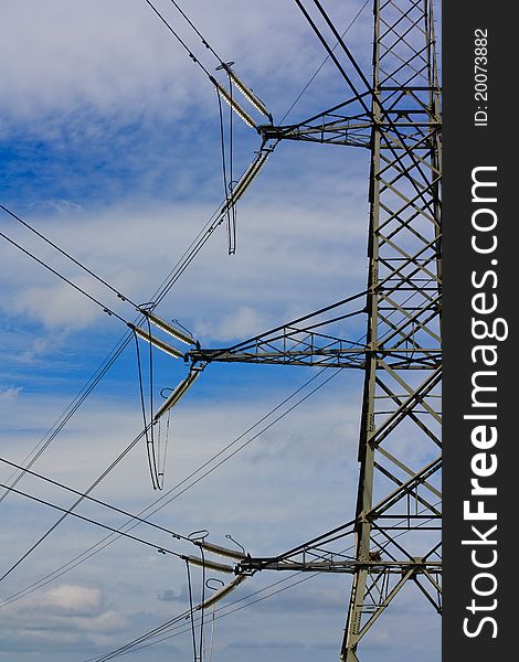 A metal electricity pylon against a blue cloudy sky. A metal electricity pylon against a blue cloudy sky