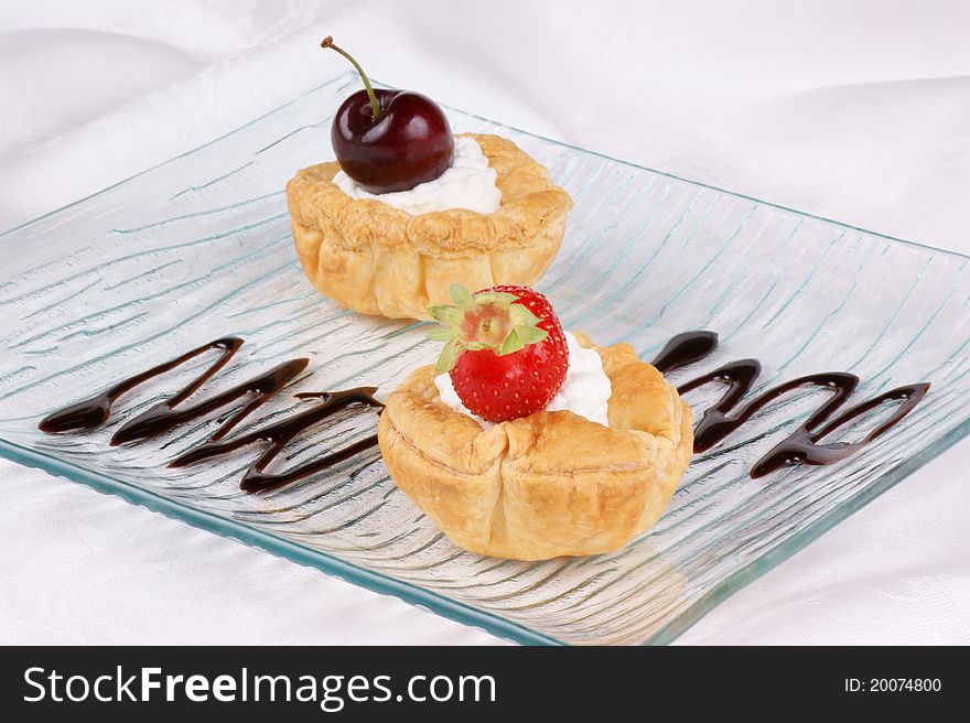 Fruit tarts on a glass plate decorated with chocolate topping