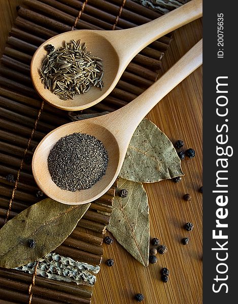 Pepper, cumin and bay leaf on wooden plate