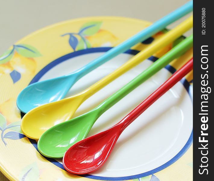 Red, yellow, green and blue spoons on the plate. Red, yellow, green and blue spoons on the plate